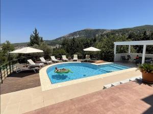 a swimming pool with two people in a swimming pool at villa Aphrodite Maritsa in Pastida