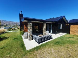 ワナカにあるHawea Heaven: Superking beds + Hot Tub + Mountainの黒屋根と石の煙突のある家