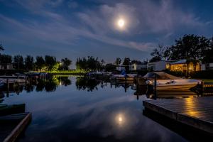 aocked boats in a marina at night with a full moon at Camping Kleine Belterwijde, Haven Chalet in Belt-Schutsloot +8 photos