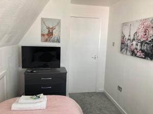 a bedroom with a tv and a bed with a pink blanket at Park View House in Maghull