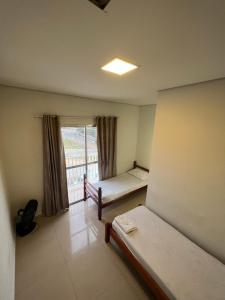 een kleine kamer met 2 bedden en een raam bij Pousada viracopos in Campinas
