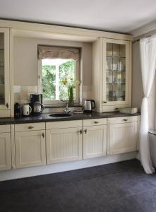 a kitchen with white cabinets and a window at The Cosy Cottage in Zeewolde