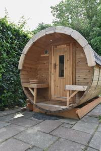 a wooden sauna with a large woodenorthole in a garden at The Cosy Cottage in Zeewolde