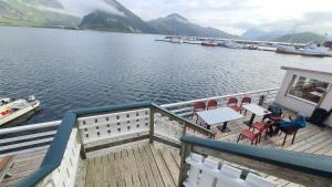 a deck of a boat with tables and chairs on the water at Lydersen Rorbuer Budget Hostel & Private Apartments in Fredvang +59 photos