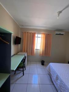 a bedroom with a bed and a desk and a window at Hotel Peritoró in Peritoró