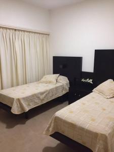 1 dormitorio con 2 camas, vestidor y cortinas en Departamento de categoría en corazón de Miramar en Miramar