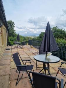 a patio with tables and chairs and an umbrella at Lakeside cottage in Huddersfield