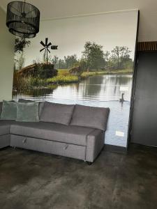a couch in a room with a large painting of a lake at Wiede lodge met uitzicht over het water in Belt-Schutsloot