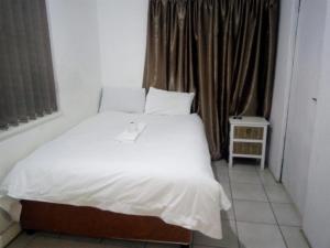 a bed with white sheets and pillows in a room at MEDUPI 2 Guesthouse. in Kempton Park