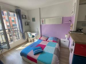 a bedroom with a colorful bed and a kitchen at Paris Saint Maurice Montgolfier in Saint-Maurice