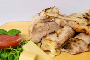 un plato de comida con pollo, queso y salsa en Lux apartments and rooms Dogs baronesse Idrija, en Idrija