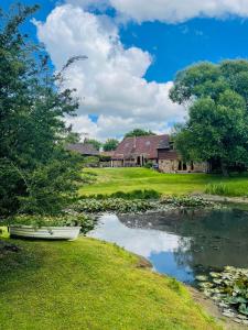 a boat on a river in front of a house at The Granary Barn- holiday home by the lake in nature in Ringmer