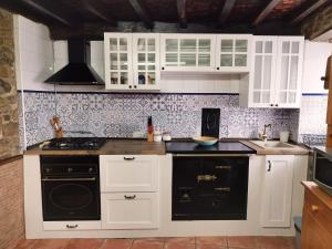 una cocina con armarios blancos y electrodomésticos negros en Casa Rural El Corquieu de la Cava, en San Feliz
