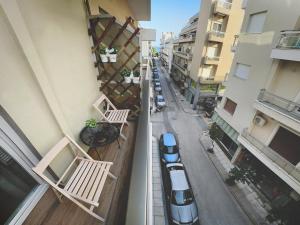 an apartment balcony with two benches and cars on a street at COMFY DEN by Cozy Stories in Alexandroupoli