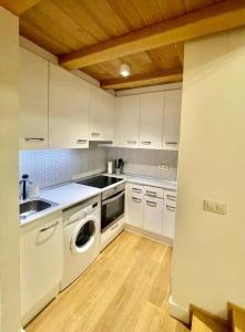 a kitchen with white cabinets and a washer at Apartamento "Villa Marinera" in Luanco