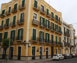 a yellow building with green shutters on a street at Piso céntrico Melilla in Melilla