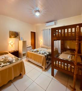 a bedroom with two beds and a bunk bed at Pousada Do Porto in Barreirinhas