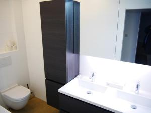 een badkamer met een toilet, een wastafel en een spiegel bij Residentie Sweetnest met hotelservice à la carte in Knokke-Heist