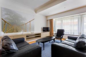 a living room with two couches and a tv at Residentie Sweetnest met hotelservice à la carte - 3 dubbel kamers in Knokke-Heist