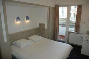 1 dormitorio con cama blanca y ventana en Residentie Sweetnest met hotelservice à la carte en Knokke-Heist