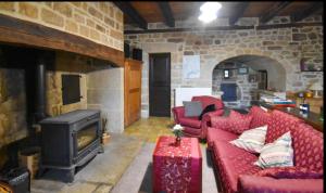 a living room with red couches and a stone fireplace at Gite Les Sources in Marcillac-la-Croisille