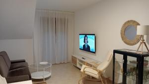 sala de estar con sofá y TV en la pared en ATICO A 3 KM DE SANXENXO CON PISCINA Y GARAJE en Sanxenxo