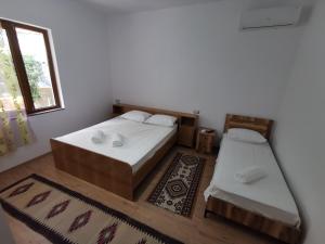 a bedroom with two beds and a window and a rug at Bujtina Valgent in Berat