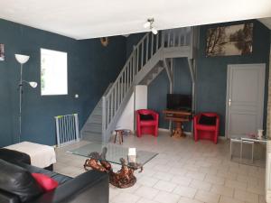 sala de estar con escalera y sillas rojas en Ferme de Barville & SPA, en Écrammeville