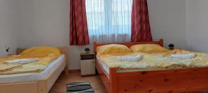 2 camas individuales en un dormitorio con cortinas rojas en Balassa Családi Apartman, en Vonyarcvashegy