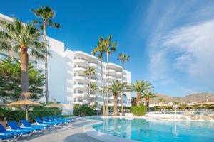 a resort with a swimming pool with chairs and palm trees at Aparthotel Alcudia Beach in Port d'Alcudia