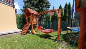 un parque infantil de madera con columpio y columpio en Balassa Családi Apartman, en Vonyarcvashegy