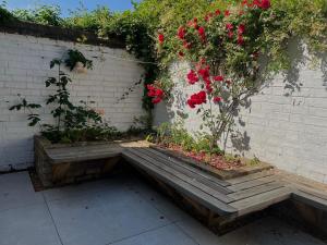 a wooden bench with red flowers on a brick wall at 300m to Fitzwilliam museum 3 en-suites double bedroom Victoria house in Cambridge