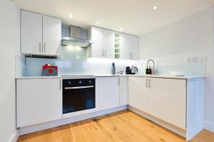 cocina con armarios blancos y lavavajillas negro en Spacious West Hampstead Apartment with mezzanine bedroom by Concept Apartments, en Londres