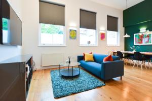 sala de estar con sofá azul y mesa en Spacious West Hampstead Apartment with mezzanine bedroom by Concept Apartments, en Londres