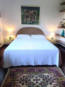 ein Schlafzimmer mit einem weißen Bett mit zwei Lampen und einem Teppich in der Unterkunft Chez Queen B&B in Lurate Caccivio