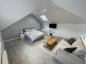 um quarto no sótão com uma cama e um sofá em Welcome properties - Self Check-In whole apartment em Swindon