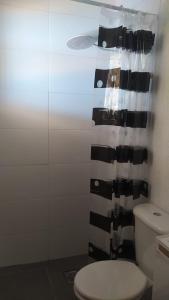 a bathroom with a toilet and a shower curtain at Espaço Viagi Hostel in Taubaté