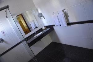 a bathroom with a sink and a mirror and towels at Constantino Hotel e Eventos in Juiz de Fora