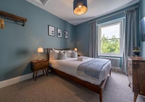 um quarto com uma cama com paredes azuis e uma janela em Clifton Town House with Cinema Room Perfect for Groups, Families, Friends Hens & Stags! em Bristol