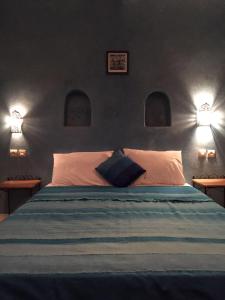 a bedroom with a bed with two lights on the wall at Nour Mogador in Ghazoua