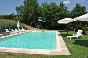 a swimming pool with chairs and an umbrella at Casa Linda in Siena