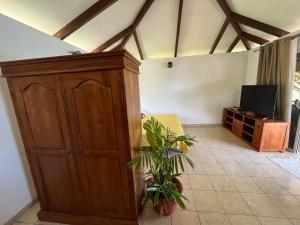 a living room with a wooden cabinet and a plant at O'coco Bungalow- Breathtaking waterfront views, endless memories in Paea