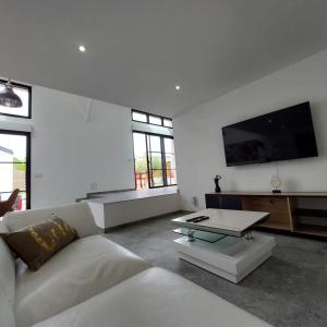 uma sala de estar branca com um sofá e uma televisão em Résidence Tamaris Loft House em La Mézière