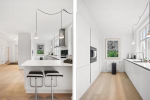 a white kitchen with white counters and stools at Dinesen Collection Luxury Condos in Copenhagen