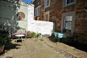 a patio with a table and chairs next to a building at Bayview- relaxing home by the sea in Saint Monance