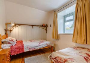 a bedroom with two beds and a window at Alpha Cottage in Dittisham