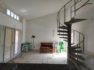 a living room with a spiral staircase and green chairs at Barreirinhas - Chalé Tubarão in Barreirinhas