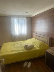 a bedroom with a yellow bed and a window at Shamakhi Nagaraxana house in Shamakhi