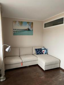 un salon avec un canapé blanc et un tableau dans l'établissement Apartament CALMA I, à Krynica Morska