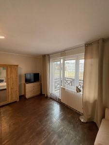 un salon avec une grande fenêtre et une télévision dans l'établissement Apartament CALMA I, à Krynica Morska
